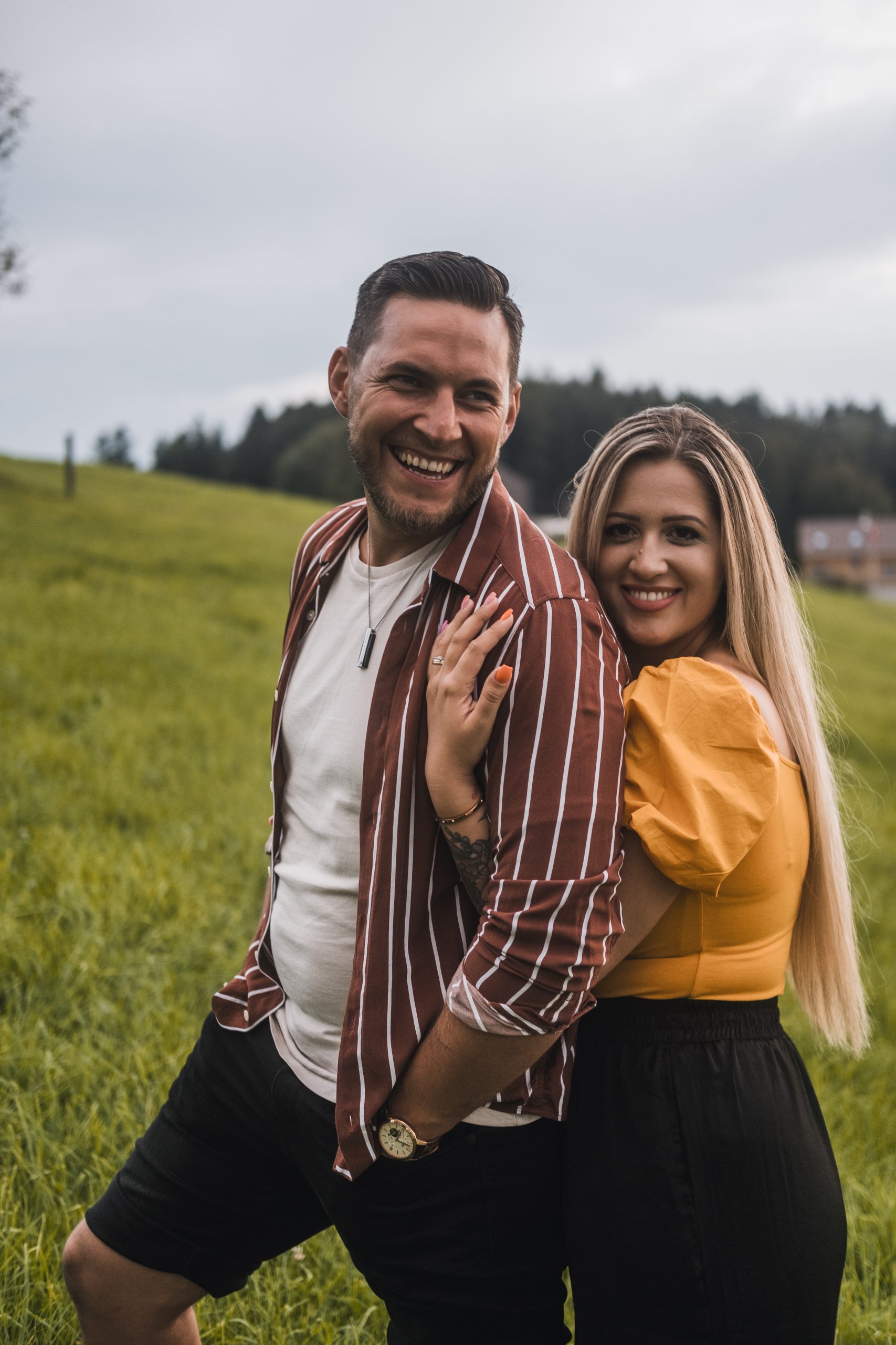 mosolygós pár jegyesfotózása a domboldalon