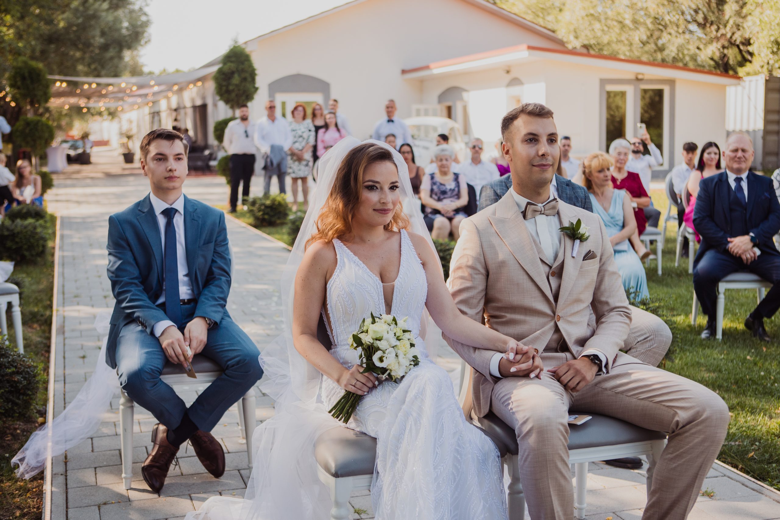 A menyasszony és a vőlegény kézenfogva hallgatják a polgári szertartás a násznép jelenlétében.