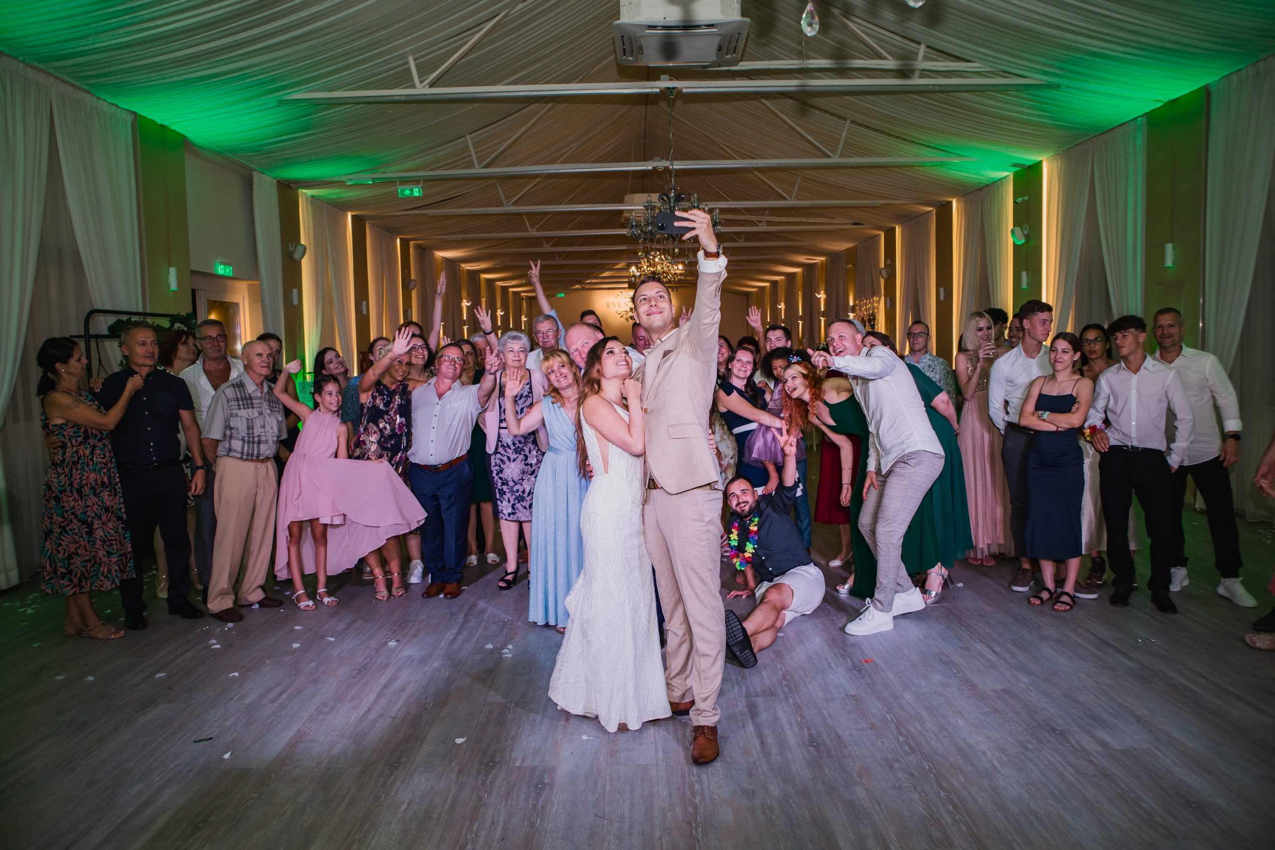Esküvői selfie a táncparketten, mindenki mosolyog.