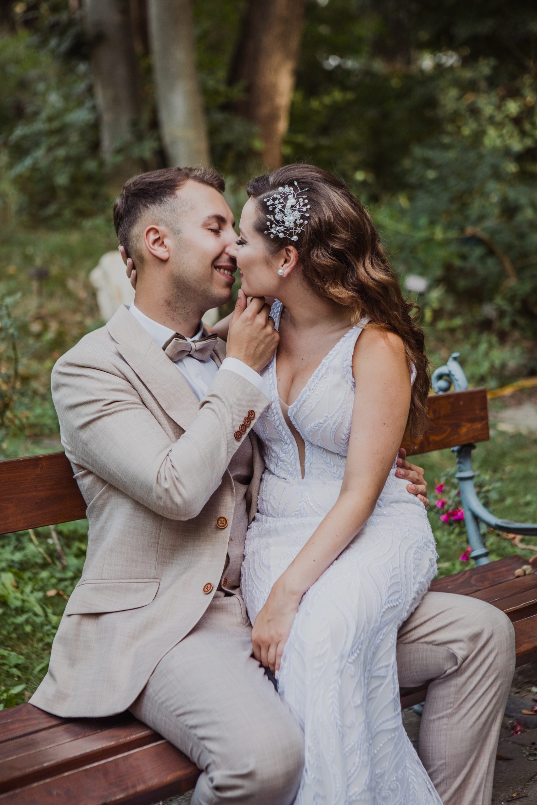 Menyasszony és vőlegény elegánsan ül a zöld növények között.