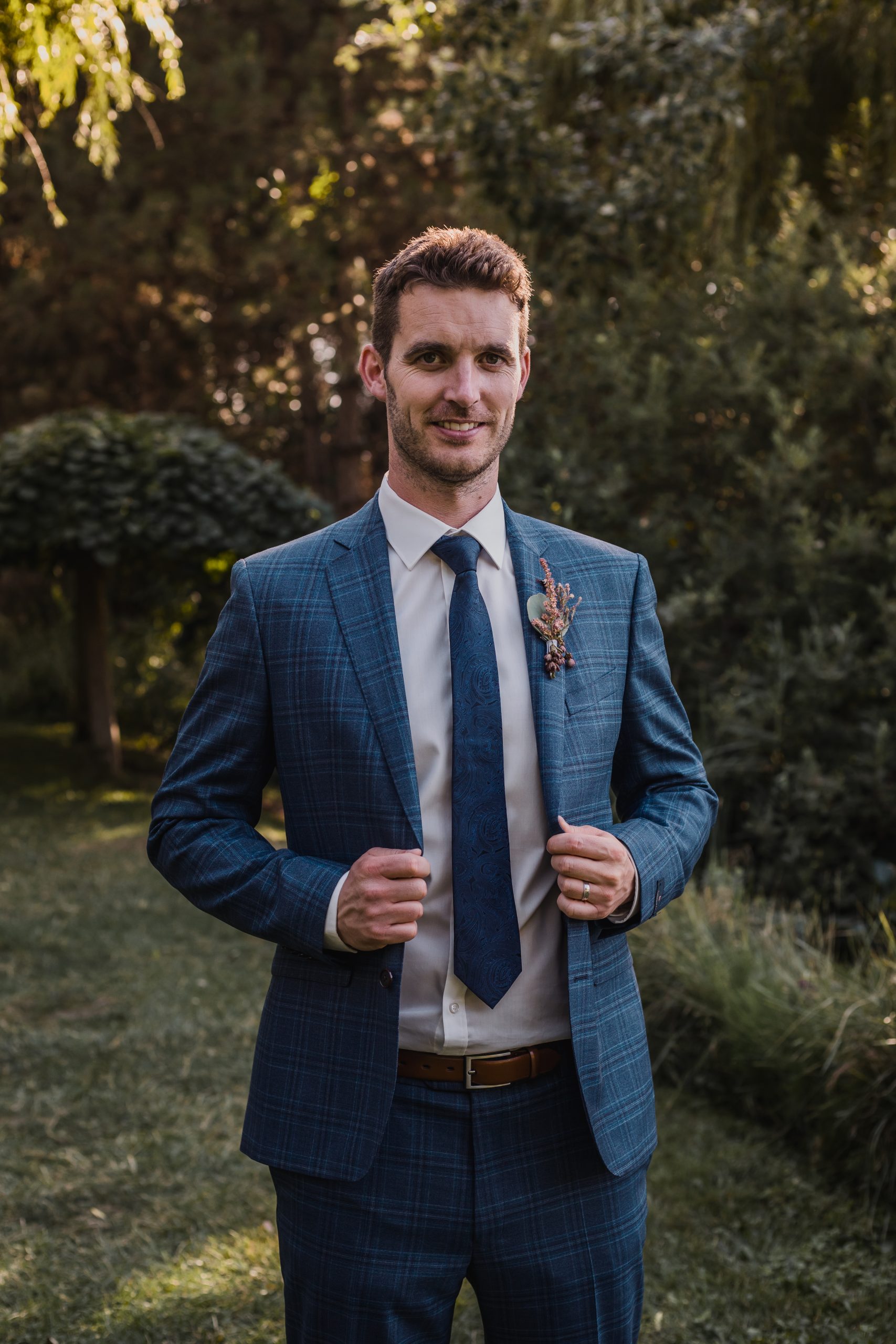 a jóképű vőlegény elegáns portréja a fák között a Bodrogi kúriában